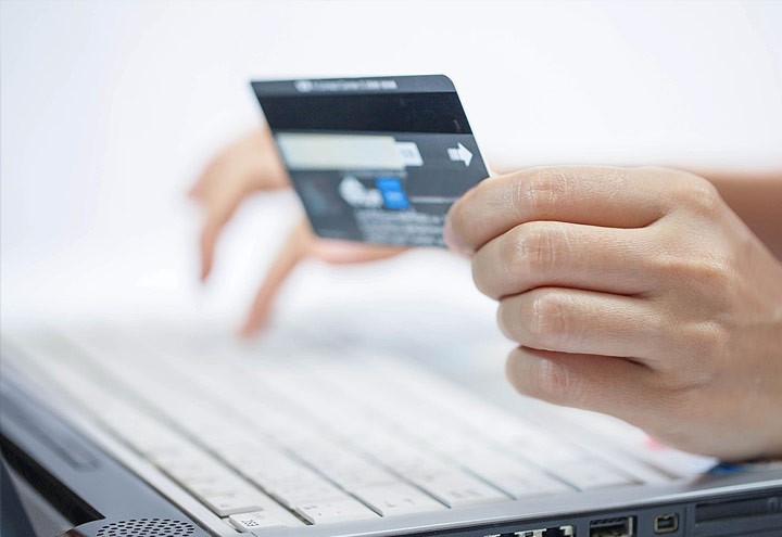 Image of holding a purchasing card in one hand and typing with another